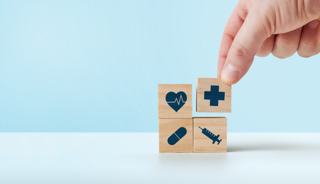 Person stacking wooden blocks with medical symbols