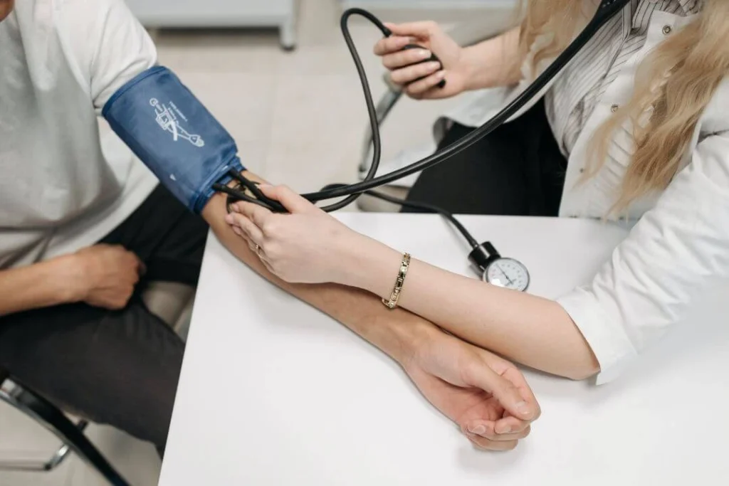 A medical professional measuring a patient's blood pressure with a sphygmomanometer in a clinical setting.