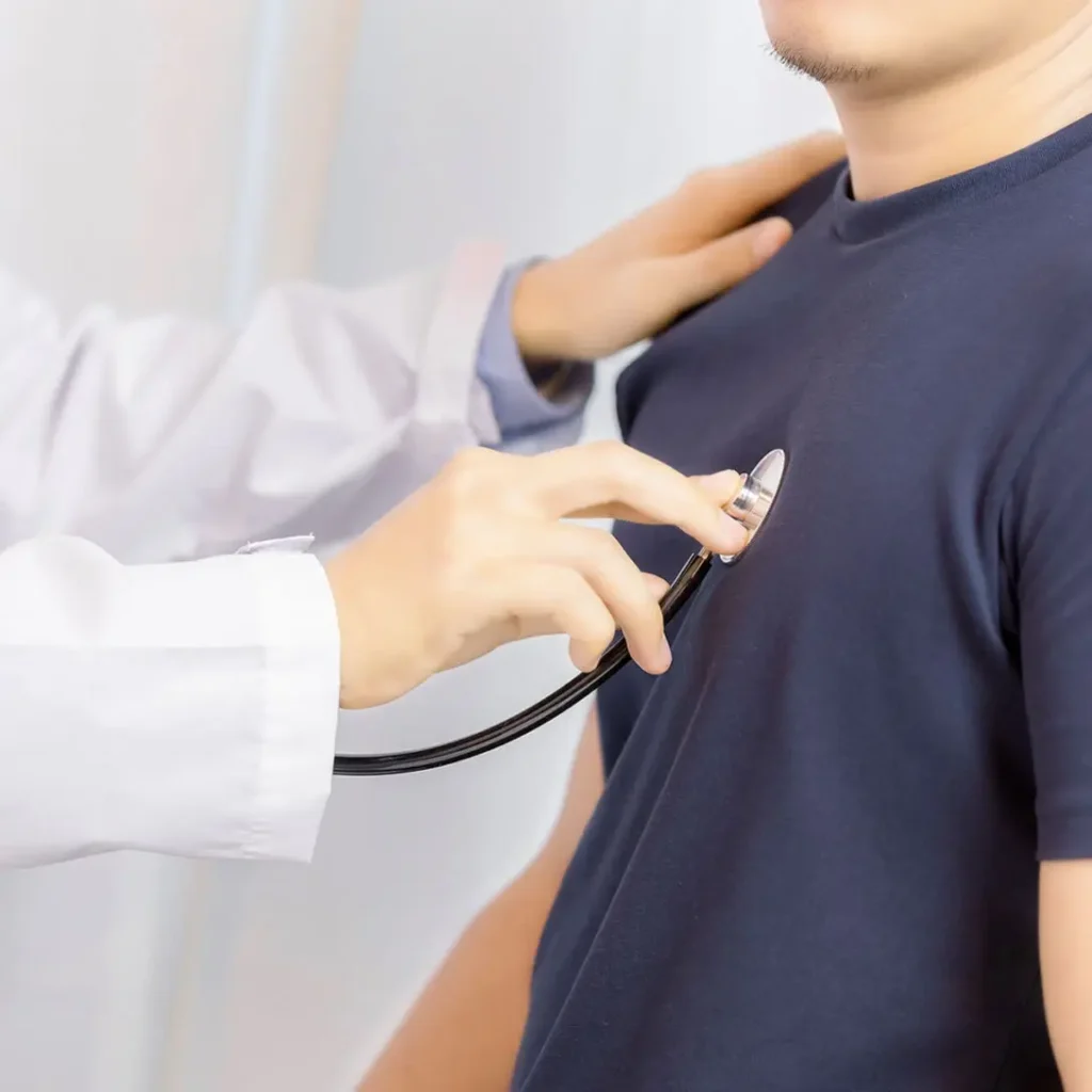 Doctor using a stethoscope to check the heartbeat of a patient in a navy blue shirt.