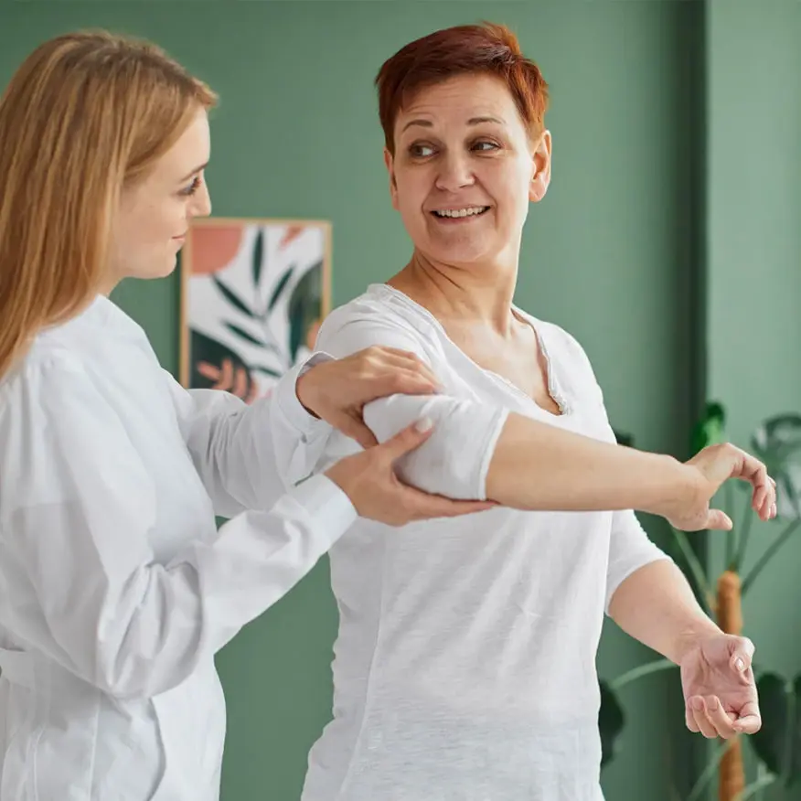 Physiotherapist assisting woman with arm exercise.