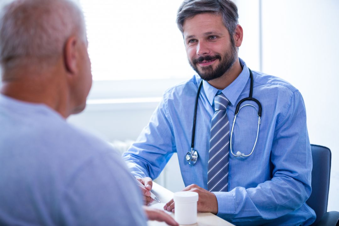 Smiling doctor discussing medication with elderly patient.