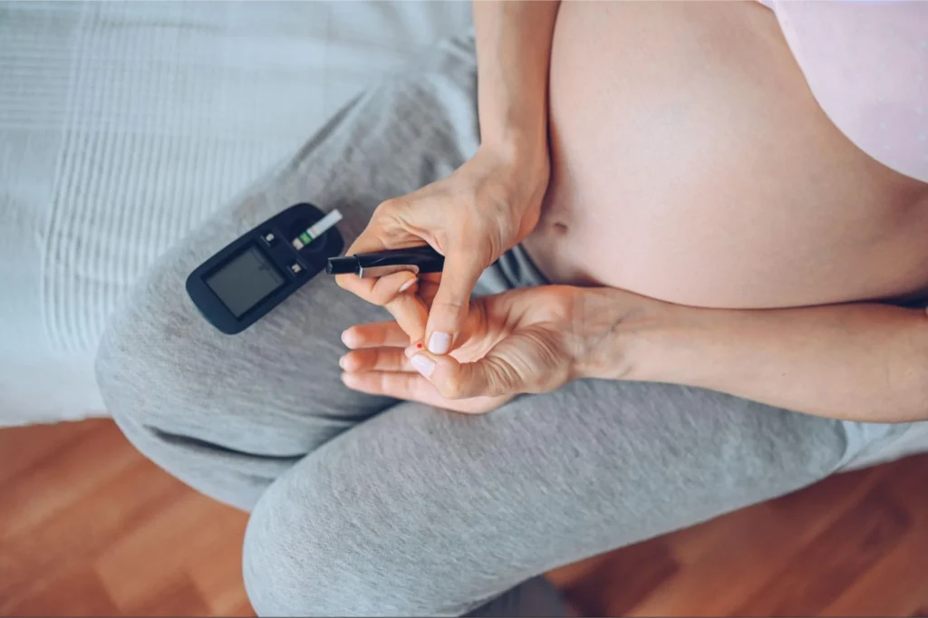 A pregnant woman checking her blood sugar levels using a glucose meter.