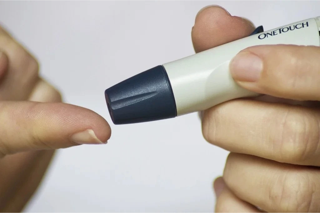 A close-up of a hand pricking a finger to check blood sugar levels.