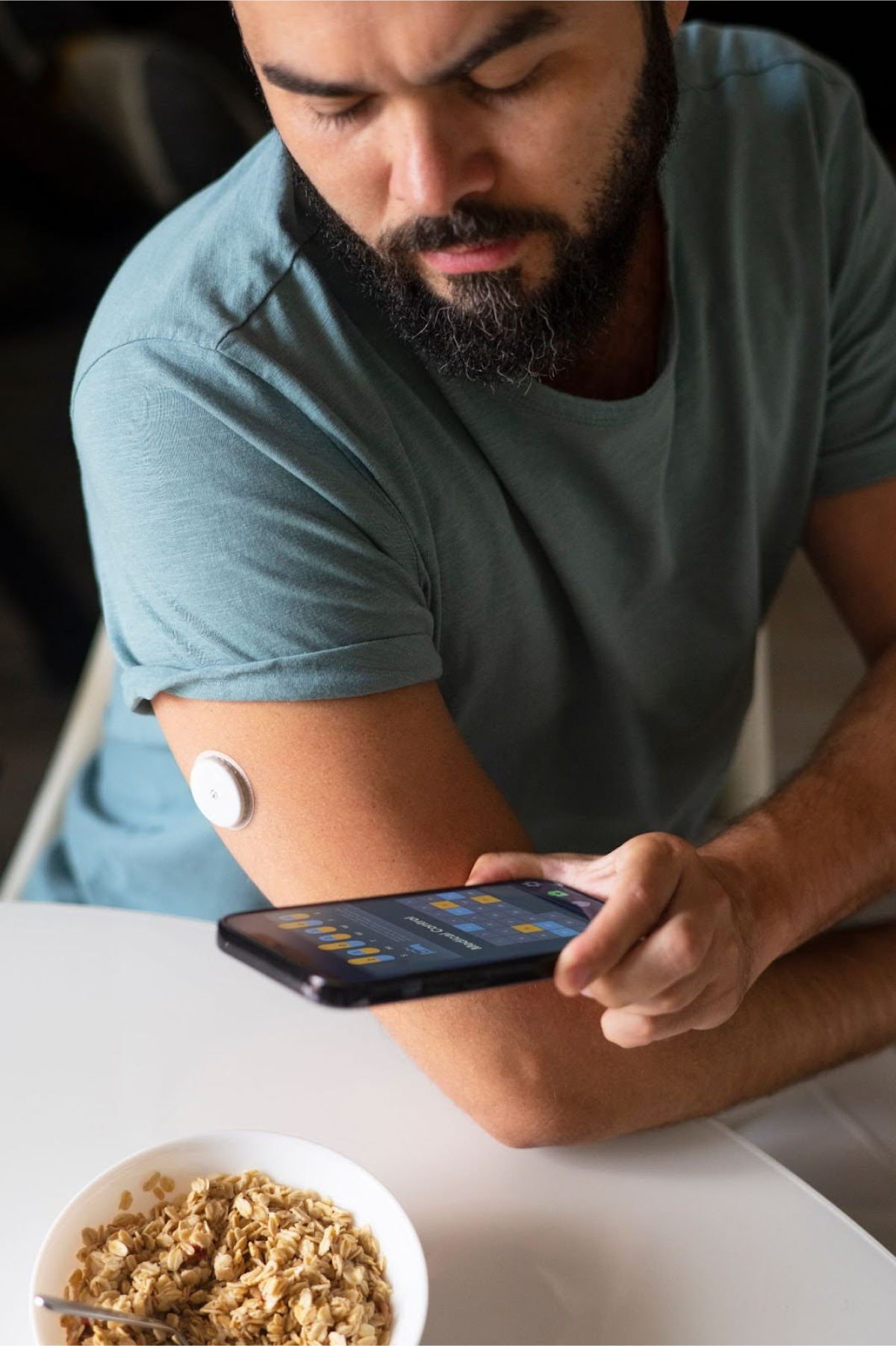 A man scanning a blood glucose monitoring patch on his arm with a smartphone app.