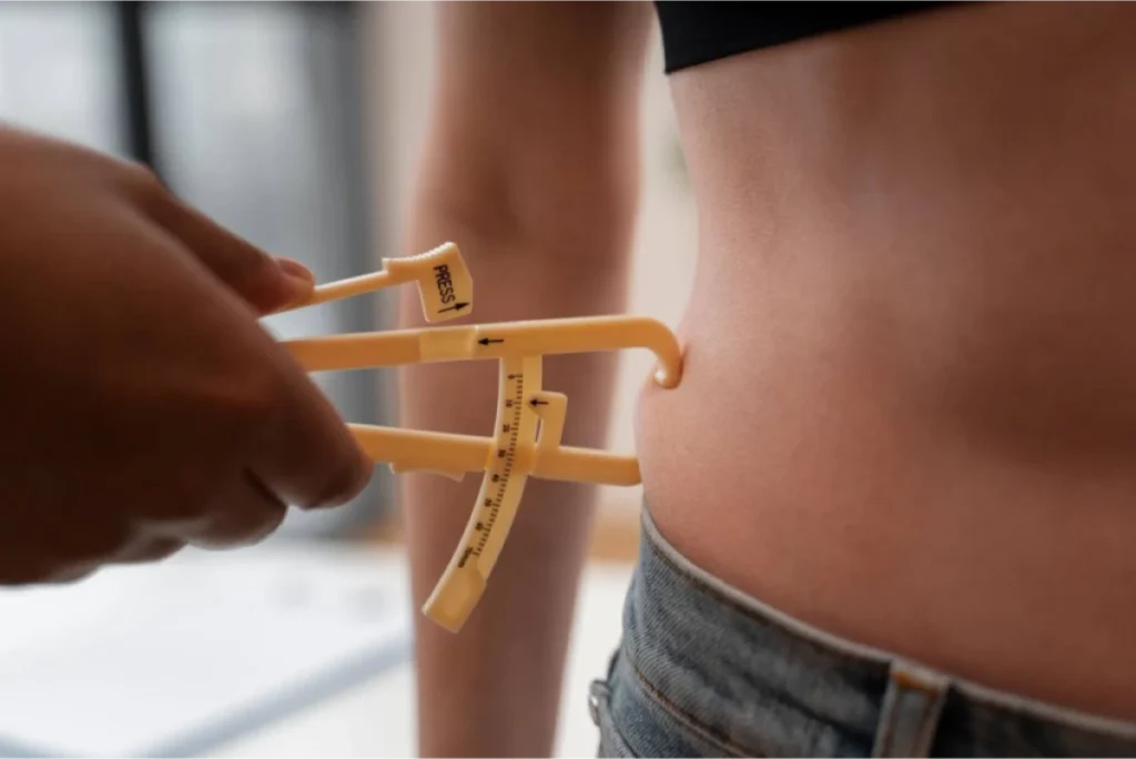 Close-up of a skinfold caliper measuring body fat on a person's waist.