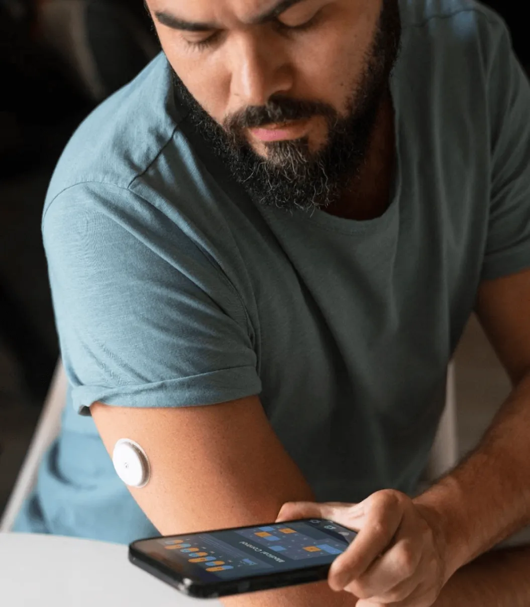 A man scanning a blood glucose monitoring patch on his arm with a smartphone app.