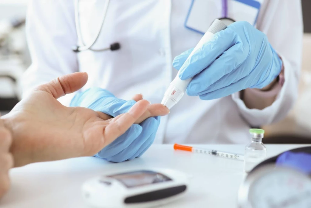 A healthcare professional wearing gloves performing a blood sugar test on a patient.