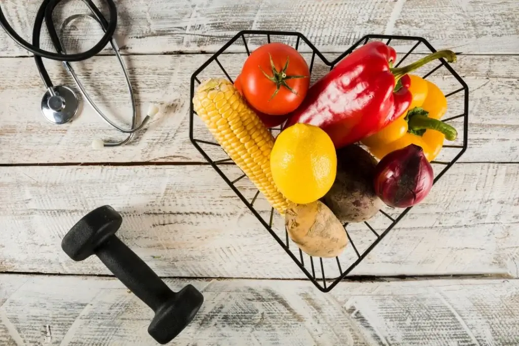 Heart-shaped basket with vegetables, a stethoscope, and a dumbbell