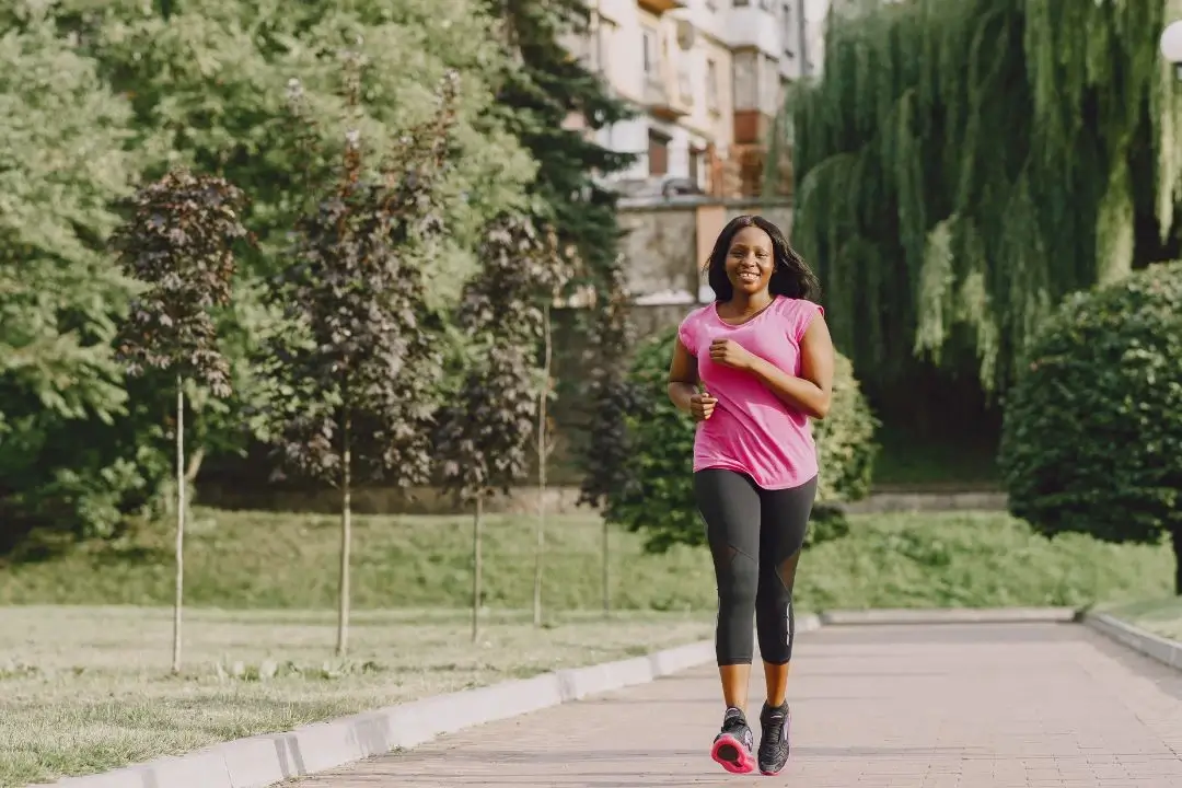 Woman jogging on a path in a park with greenery