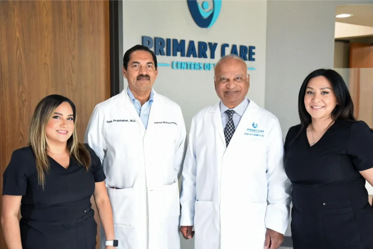 A group of four healthcare professionals standing together in front of a "Primary Care" sign