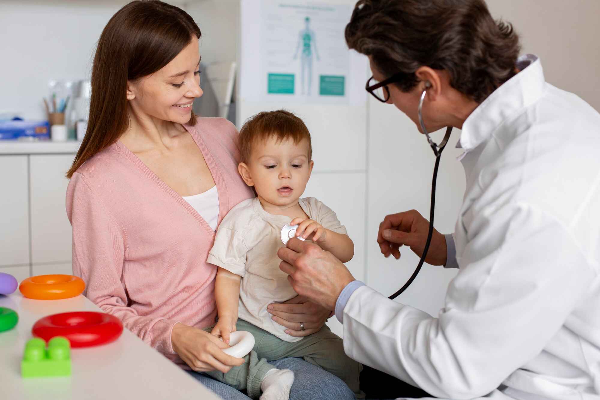 Doctor examining child while mother holds child.