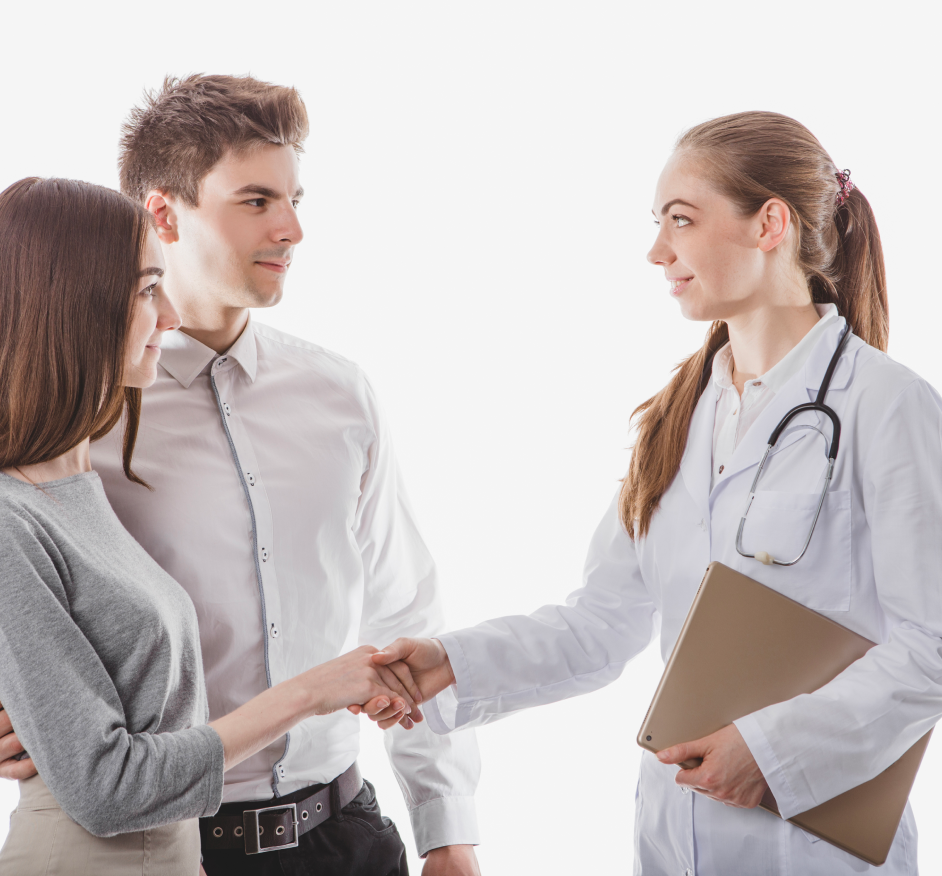 Female doctor greeting couple with handshake, smiling.